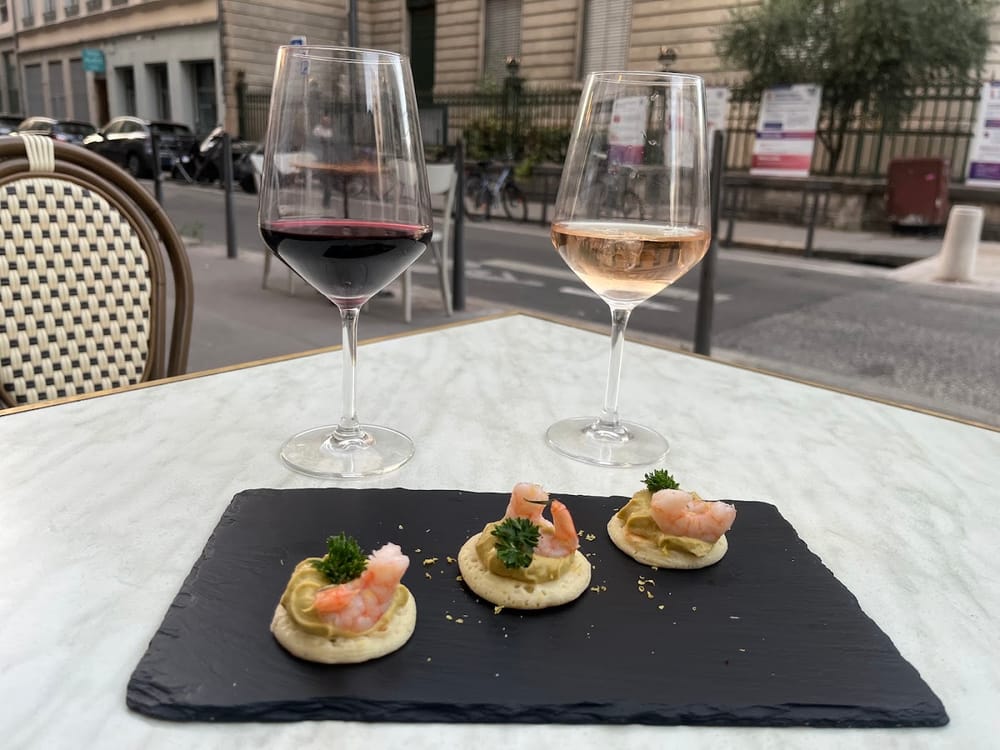 Ein Glas Rotwein, ein Glas Rosé und Garnelen-Canapés auf einer Schieferplatte